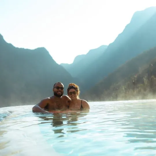 Couple relaxing in natural thermal pools surrounded by mountains. A hidden gem near the main Mexico City Tours.