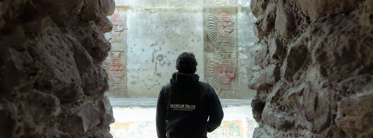 Visitor looking at ancient murals through a stone archway. Discover the mysteries on a Teotihuacan pyramids tour.