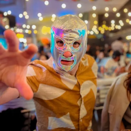 Person wearing a shiny Lucha Libre mask at a restaurant. A fun cultural experience during Mexico City Tours.