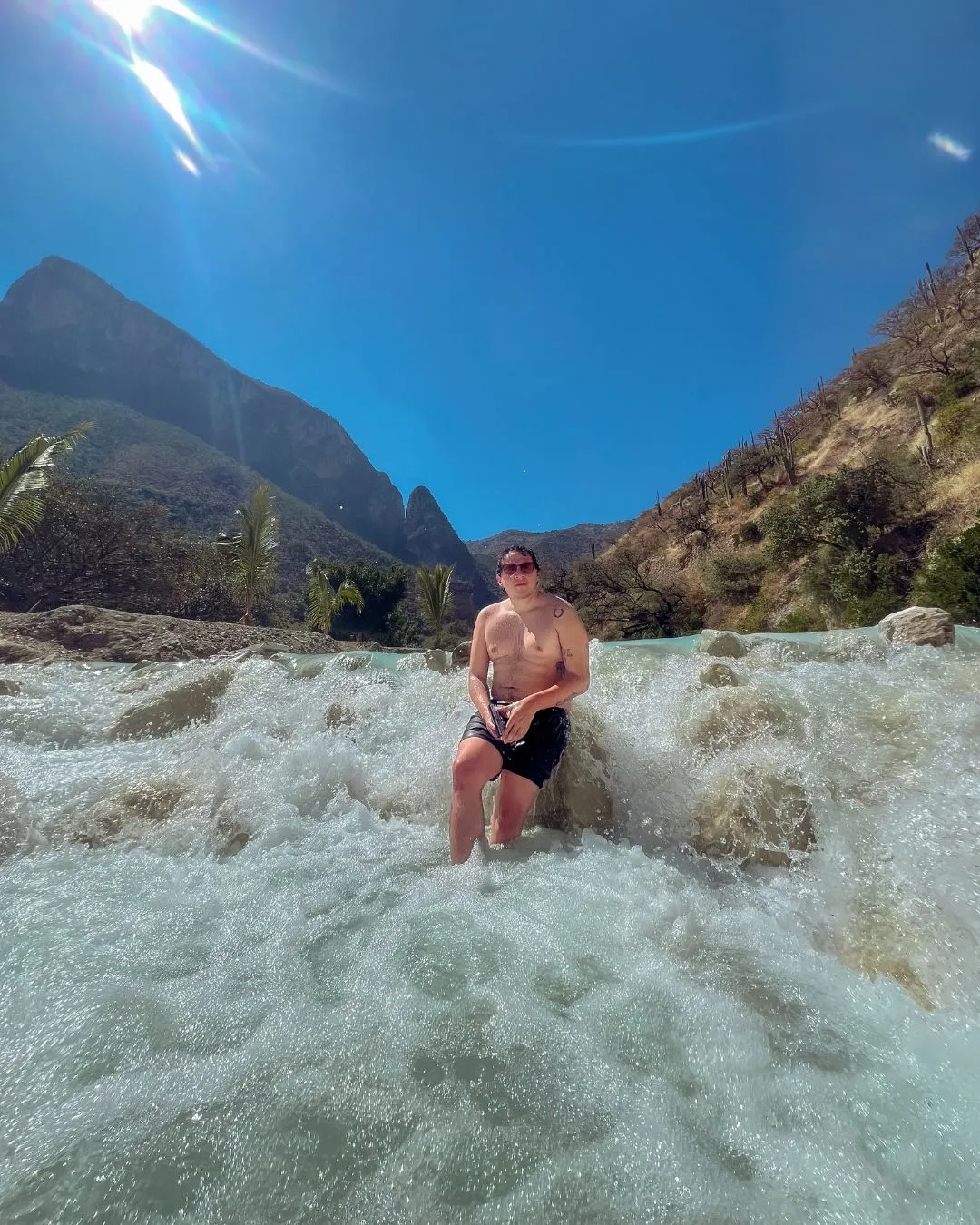 The power of nature with Tolantongo tours: Man enjoying the strong, rushing current of the hot spring river.Recharging Energy: