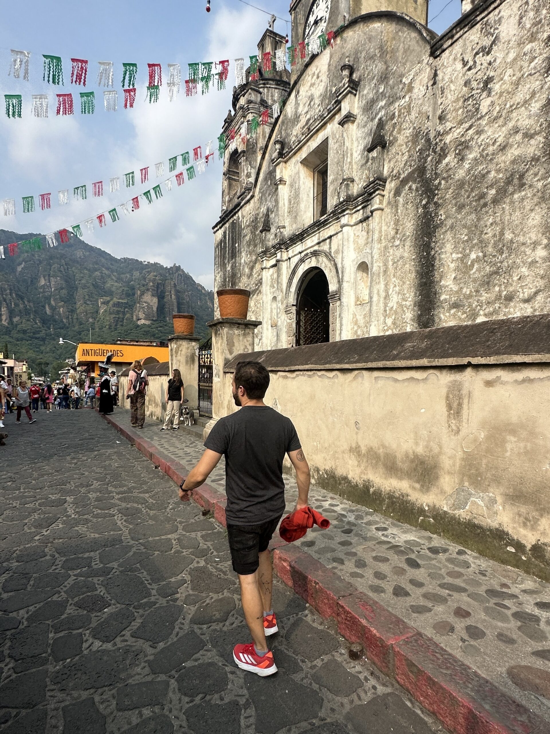 A man walks along a cobblestone street toward the historic Parroquia de la Natividad during one of our Tepoztlan tours.