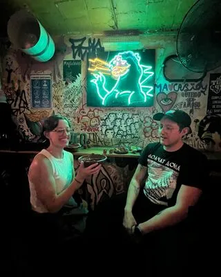 Tourists enjoying a drink at a vibrant, graffiti-covered bar after watching the Lucha Libre show with Mexican Tales.