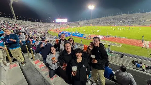 Group of friends enjoying drinks while watching a live football match at one of the iconic sports stadiums in Mexico.