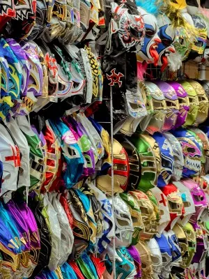 A vibrant display of colorful wrestling masks for sale outside a Lucha libre Mexico City venue for fans to buy.