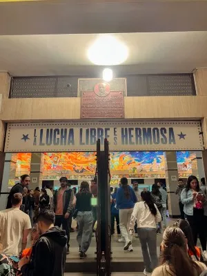 Fans entering the arena under a sign saying Lucha Libre is Beautiful for a Lucha libre Mexico City wrestling night.