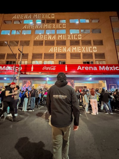 Crowds outside Arena Mexico at night; fans asking how much does it cost to get to the fights for a Lucha Libre event.