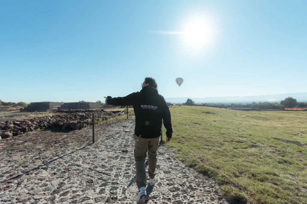 A person walking toward ancient pyramids under a bright sun, showcasing unique experiences in Mexico City outskirts.