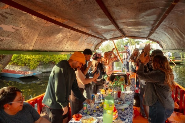 People dancing and enjoying food on a colorful trajinera, among the most popular things to do in Xochimilco.