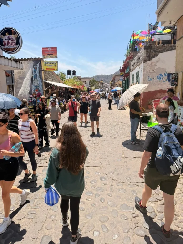 Tourists walking by food stalls and craft markets under a bright sun, fun things to do in Tepoztlan on the weekend.