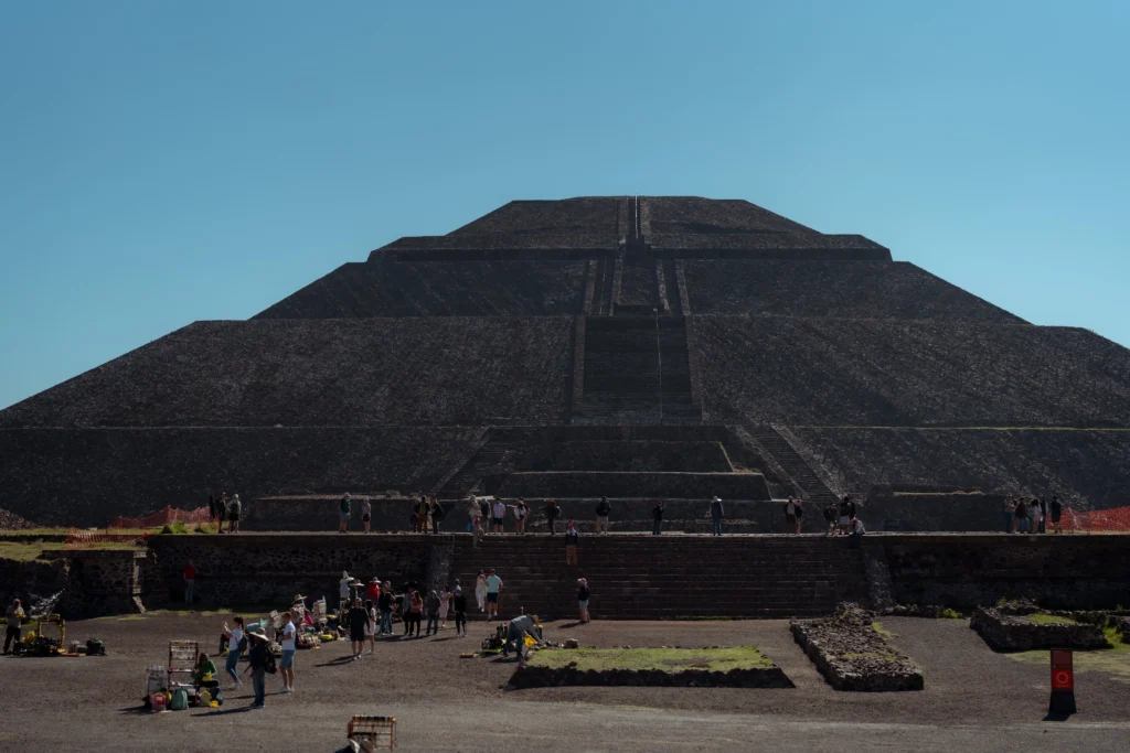 Travelers exploring the base of the massive Sun Pyramid while enjoying a guided Teotihuacan Pyramids Tour in the sun.