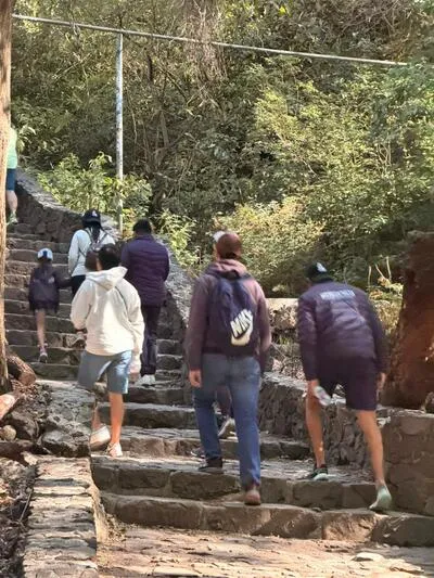 Hikers climbing a rustic stone staircase surrounded by trees on a trail to Tolantongo Hot Springs.