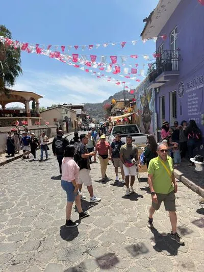Tourists walking on a cobblestone street with large mountain peaks in the background near Tolantongo Hot Springs.