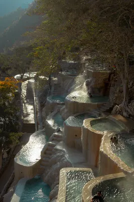Sunlight shining over cascading thermal pool terraces, representing the stunning views at Cenotes and Hot Springs near Mexico City.
