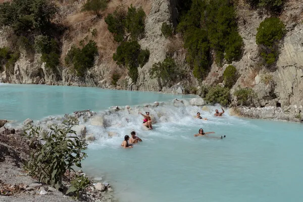 A wide-angle landscape shot of friends bathing in the turquoise water, just a short drive from popular Cenotes and Hot Springs near Mexico City.