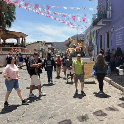 People walking on a cobblestone street decorated with colorful banners heading to Tolantongo Hot Springs.
