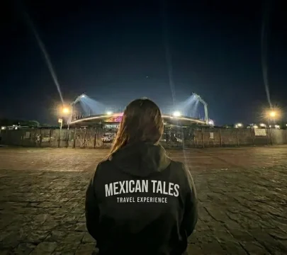 Woman looking at a lit stadium. Is Mexico City safe for tourists in 2026? Safe group tours offer night experiences.