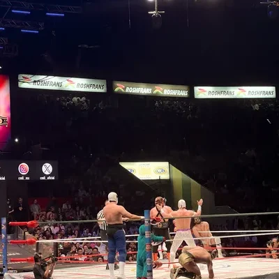 Masked luchadores and a referee inside the ring during an intense live Lucha Libre in Mexico City wrestling match.